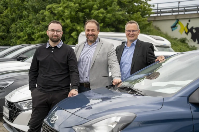 Drei Mitarbeiter von Automobile Hillebrand vor Fahrzeugen auf dem Hof